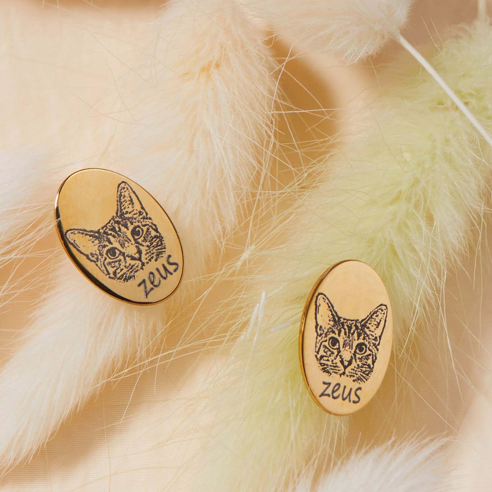 Close-up of gold oval stud earring engraved with pet portrait, custom dog earrings