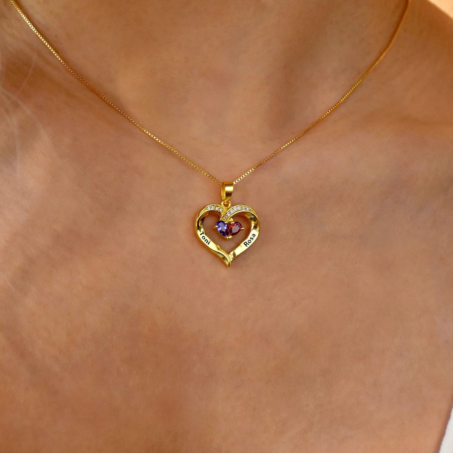 Close up of gold birthstone heart necklace worn on neck, custom engraved names
