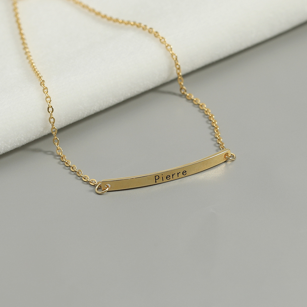 Close-up of laser engraved text on curved gold bar, personalized name bracelet detail