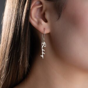 Custom cursive name earrings worn on ear, silver script dangle earring with personalized name