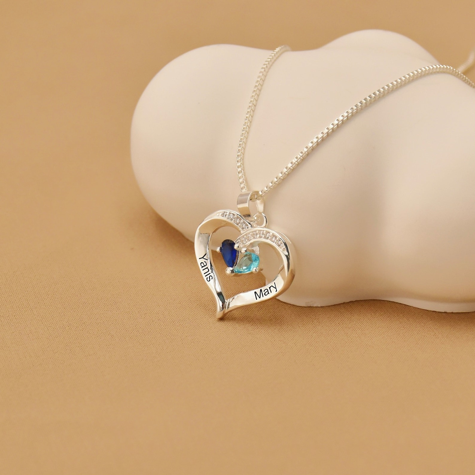 Woman wearing silver personalized birthstone heart necklace, two names pendant