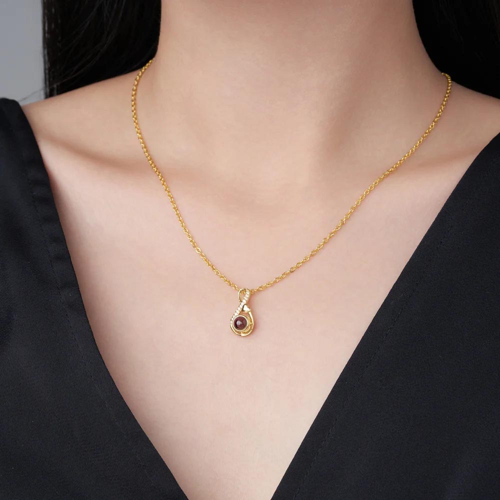 Woman wearing gold infinity photo projection necklace in black top, everyday look