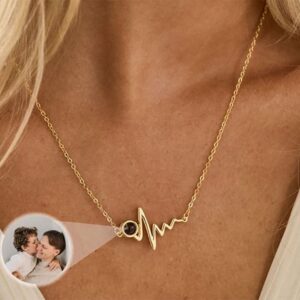 Woman wearing gold heartbeat photo projection necklace, close up on neckline