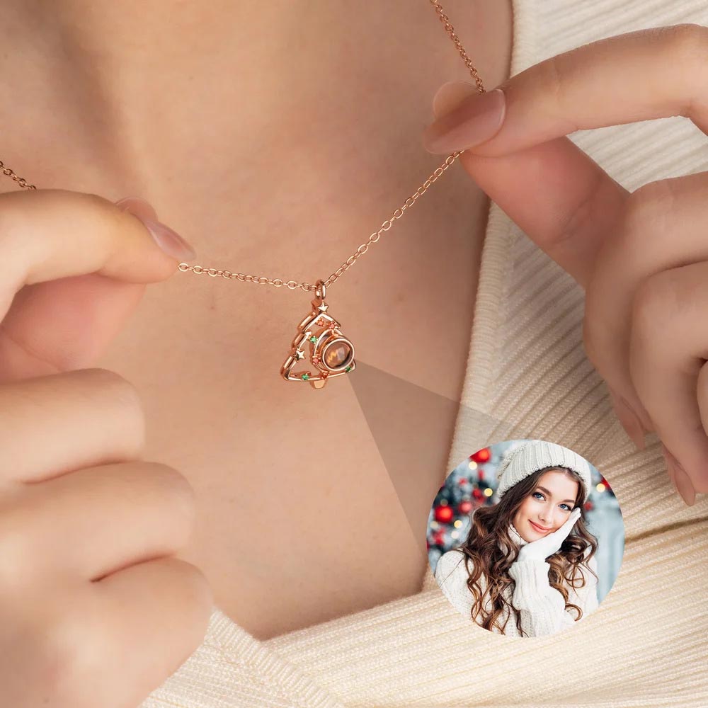 Rose gold Christmas tree photo projection necklace worn on neck, showing projected woman in winter hat photo