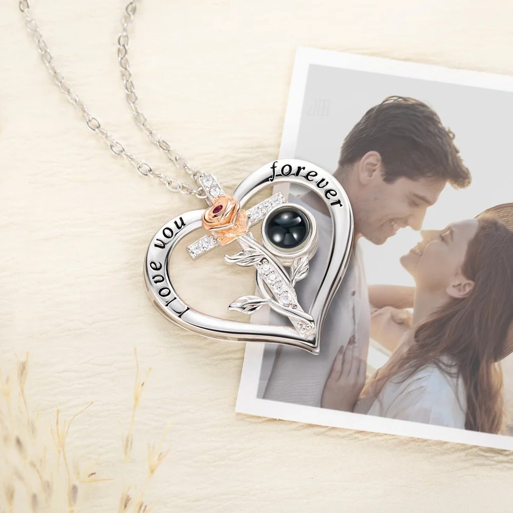 Silver heart rose cross projection necklace laid beside a couple photo, flat lay keepsake