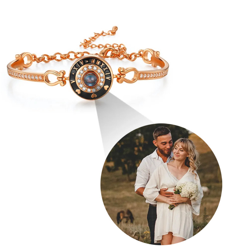 Rose gold Roman numeral clock bangle on white, couple photo projecting from central crystal
