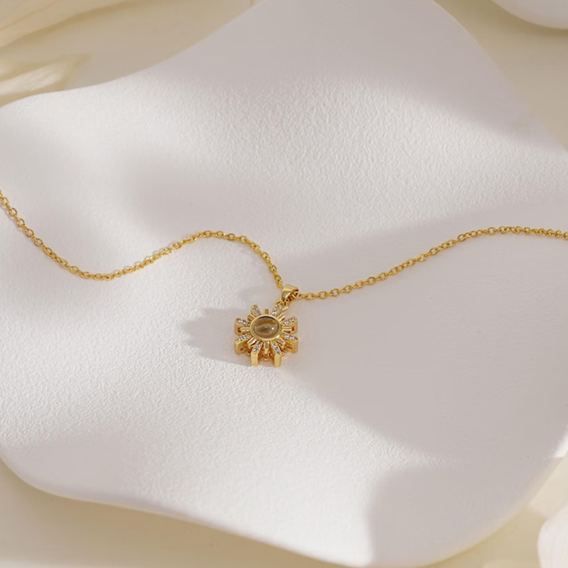 Gold sunshine sun photo projection necklace on textured white surface, radiant rays with crystal tips